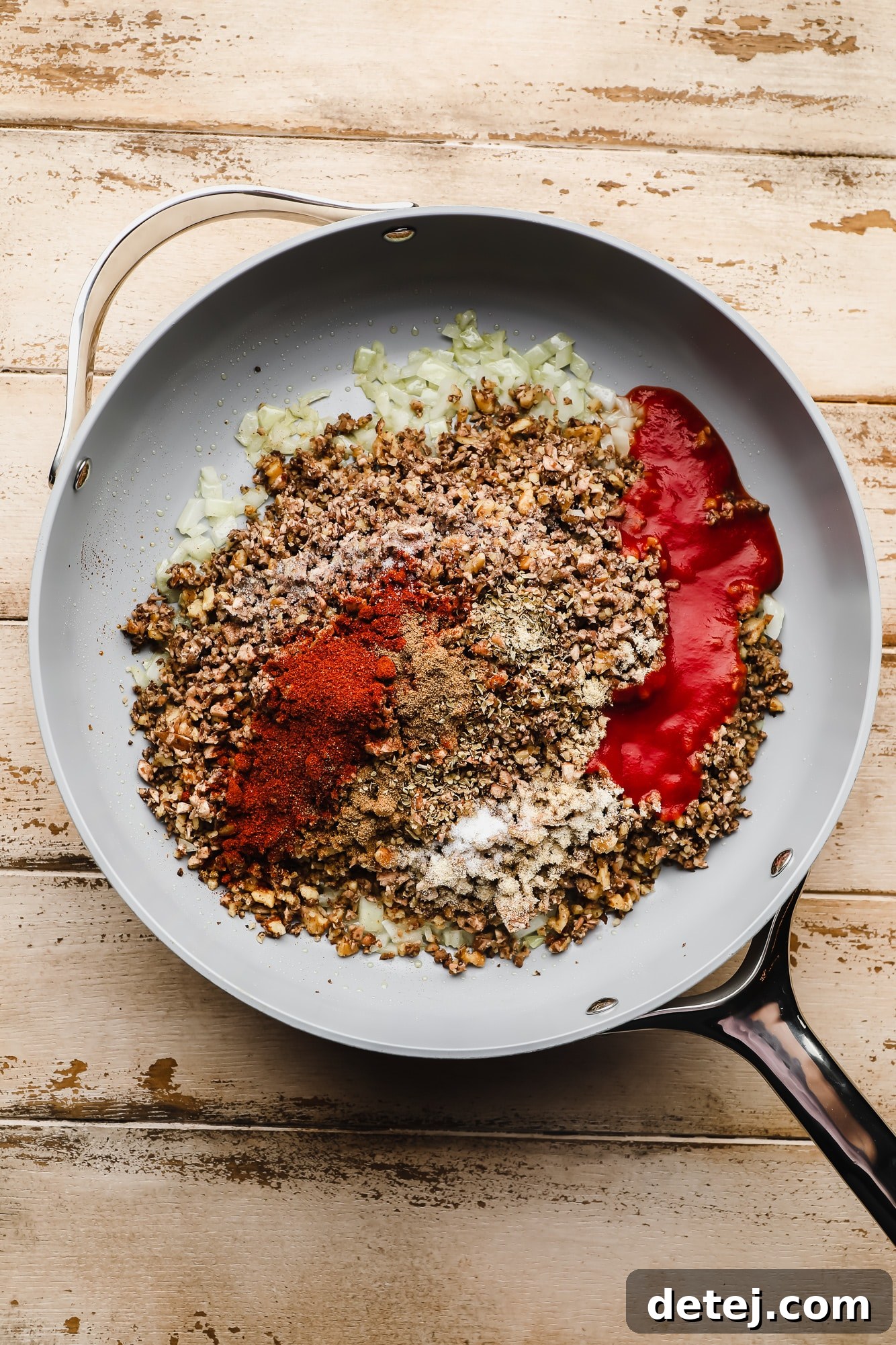 Your New Favorite Vegan Tacos 5 Vegan taco meat, made from mushrooms and walnuts, cooking in a large grey skillet with spices and tomato sauce, creating a rich, brown texture.