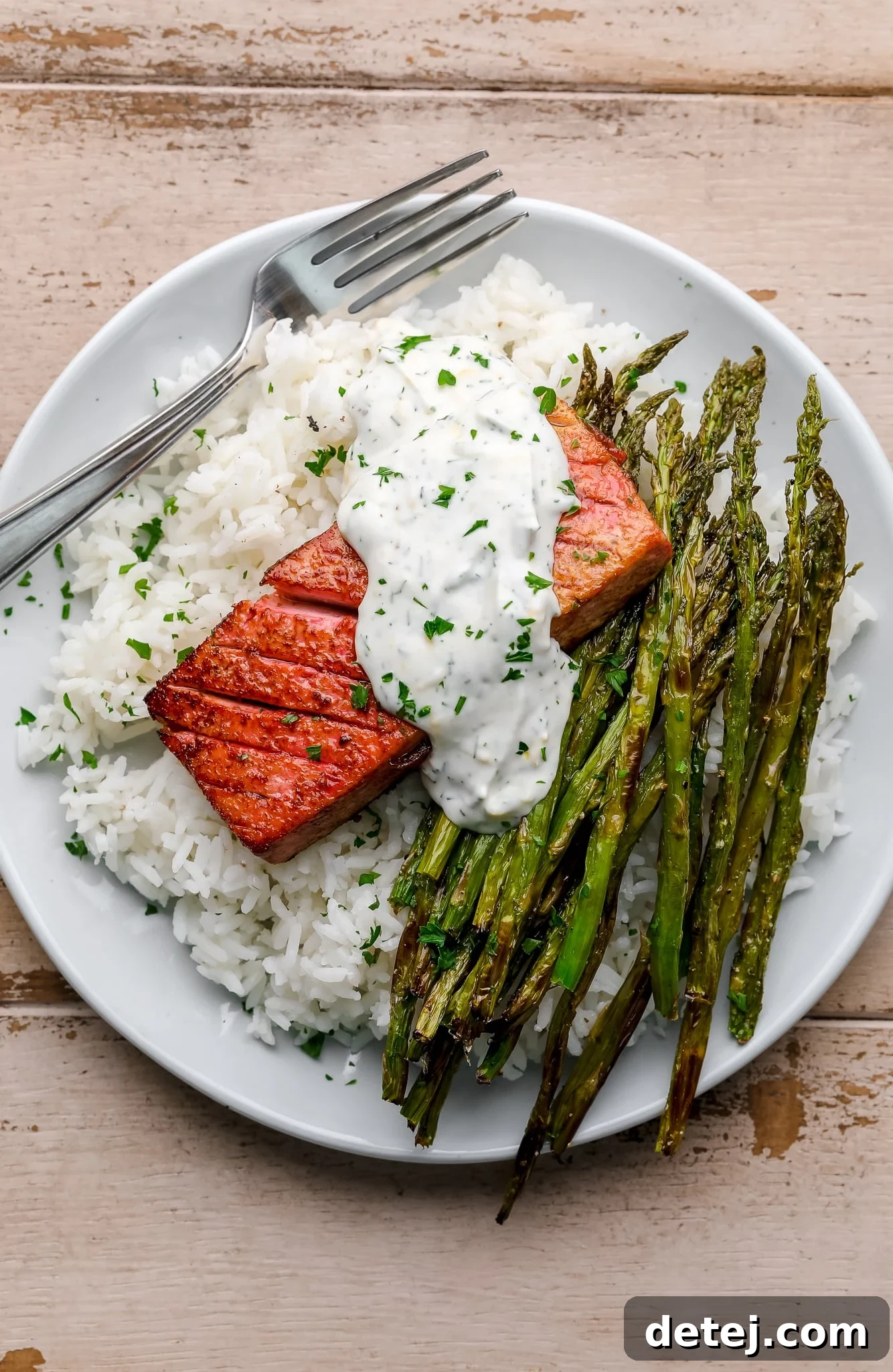 vegan salmon on a bed of rice and asparagus on a white plate.