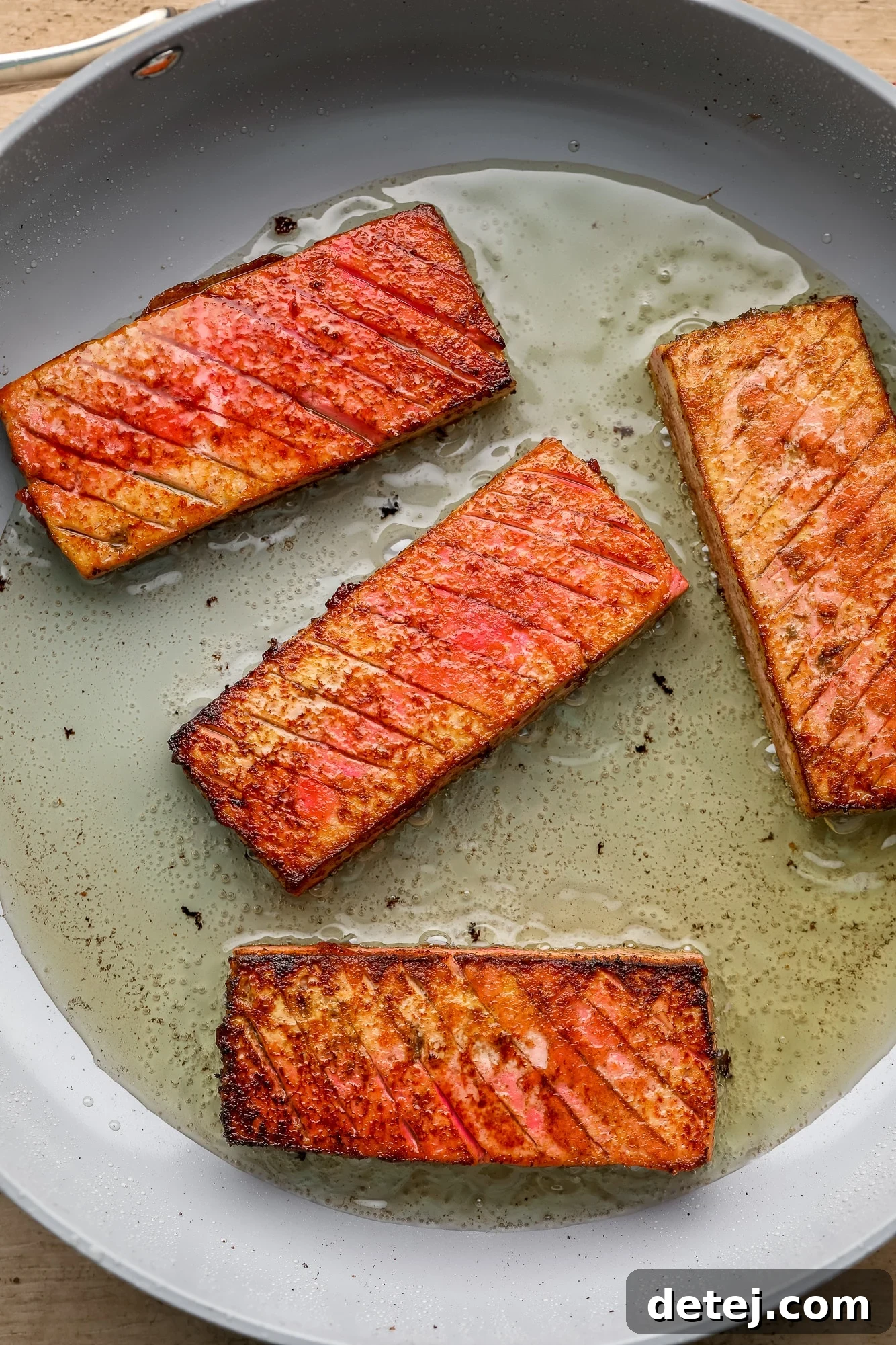 frying 4 pieces of vegan salmon in a skillet.