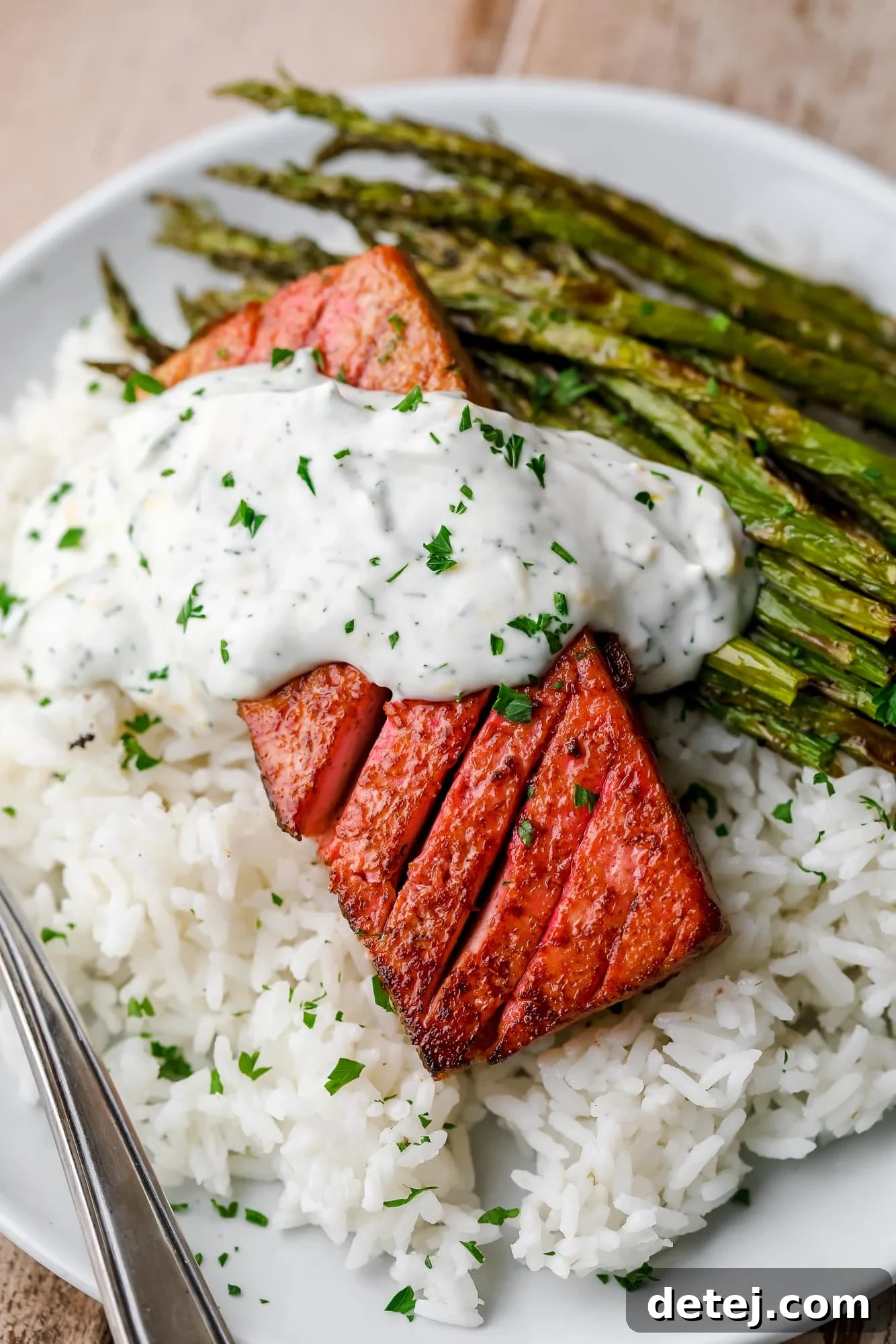 close up on a piece of vegan salmon on a bed of rice and asparagus on a white plate.