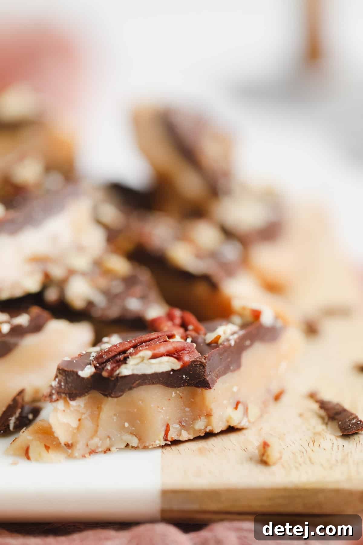 A close-up shot of a single piece of vegan toffee, rich golden brown, with more blurred toffee in the background, highlighting its texture.