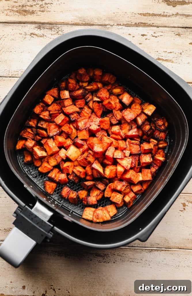 an air fryer with some cooked sweet potato chunks in it.