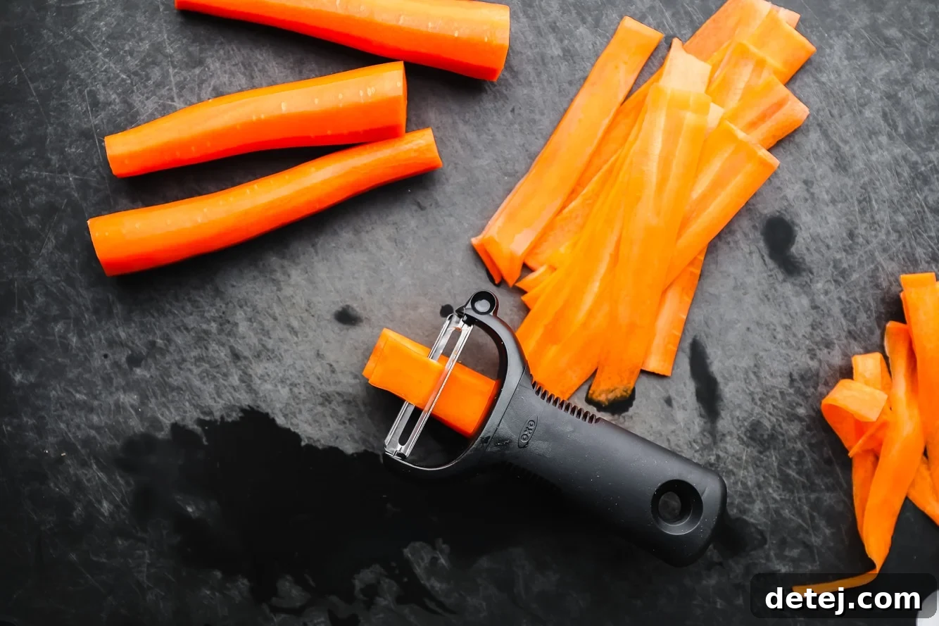 a black vegetable peeler peeling thin strips from a carrot.