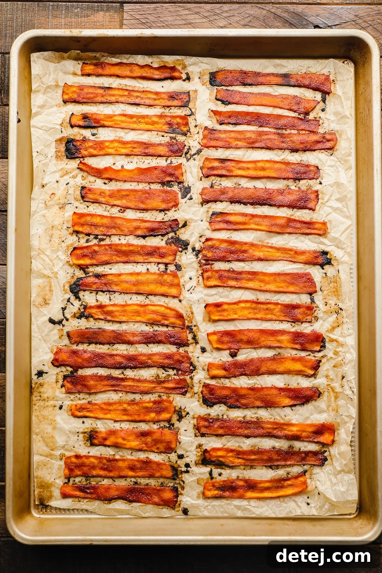 rows of baked vegan bacon on a parchment lined baking sheet.