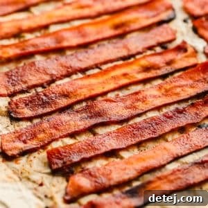 close up on strips of vegan bacon laying on a parchment-lined baking sheet.