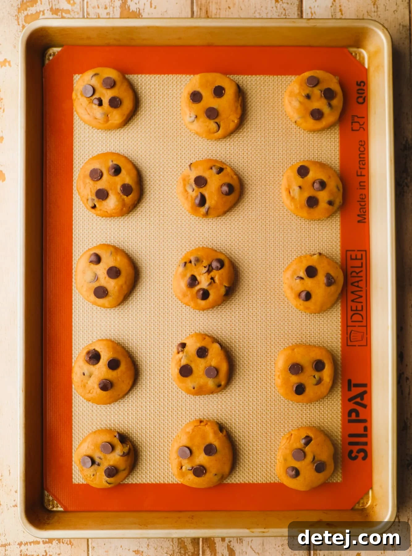 raw pumpkin chocolate chip cookie dough balls in rows on a baking sheet.