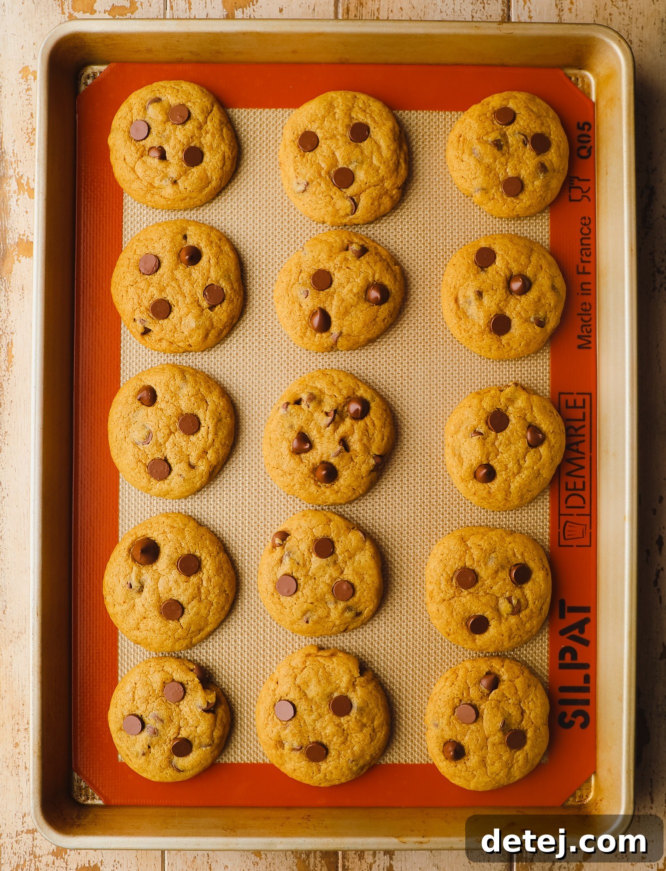 baked pumpkin chocolate chip cookies in rows on a baking sheet.