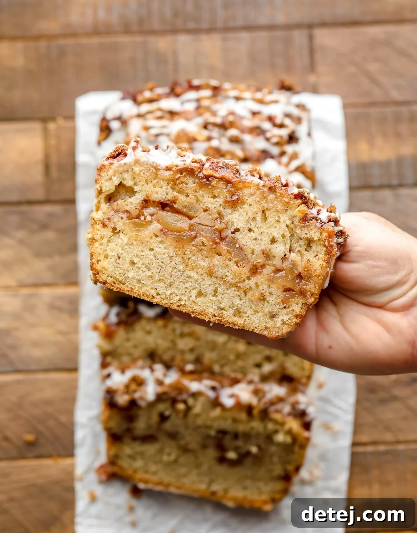 womans hand holding a slice of apple cinnamon bread.