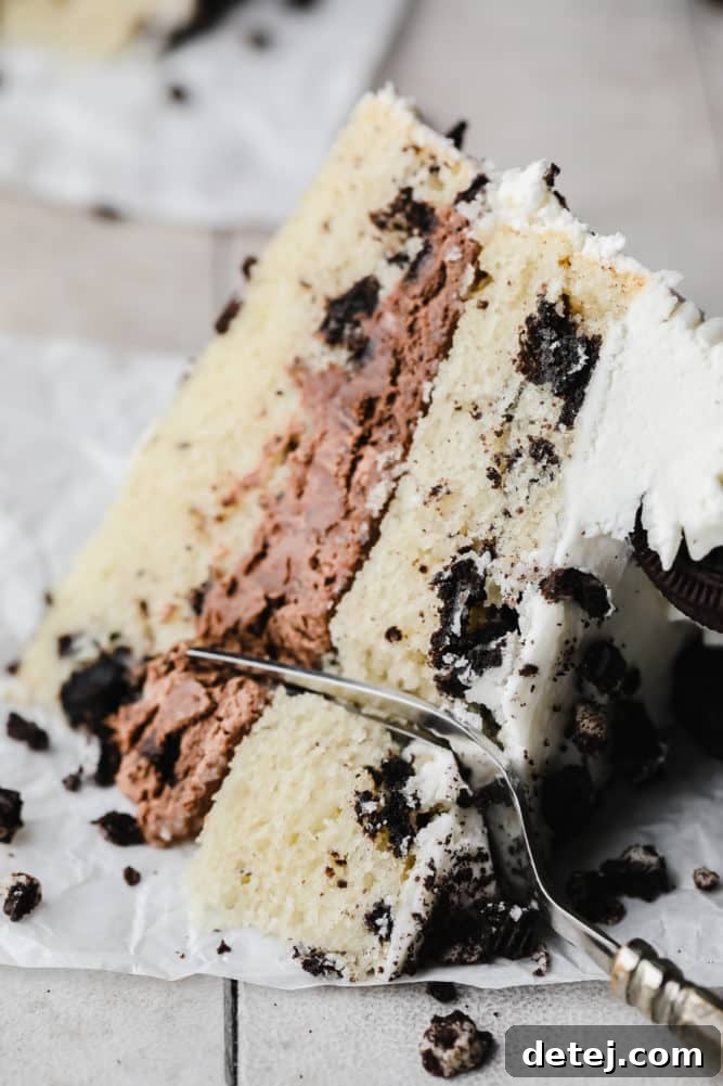 fork cutting into a piece of vegan oreo cake on grey background.
