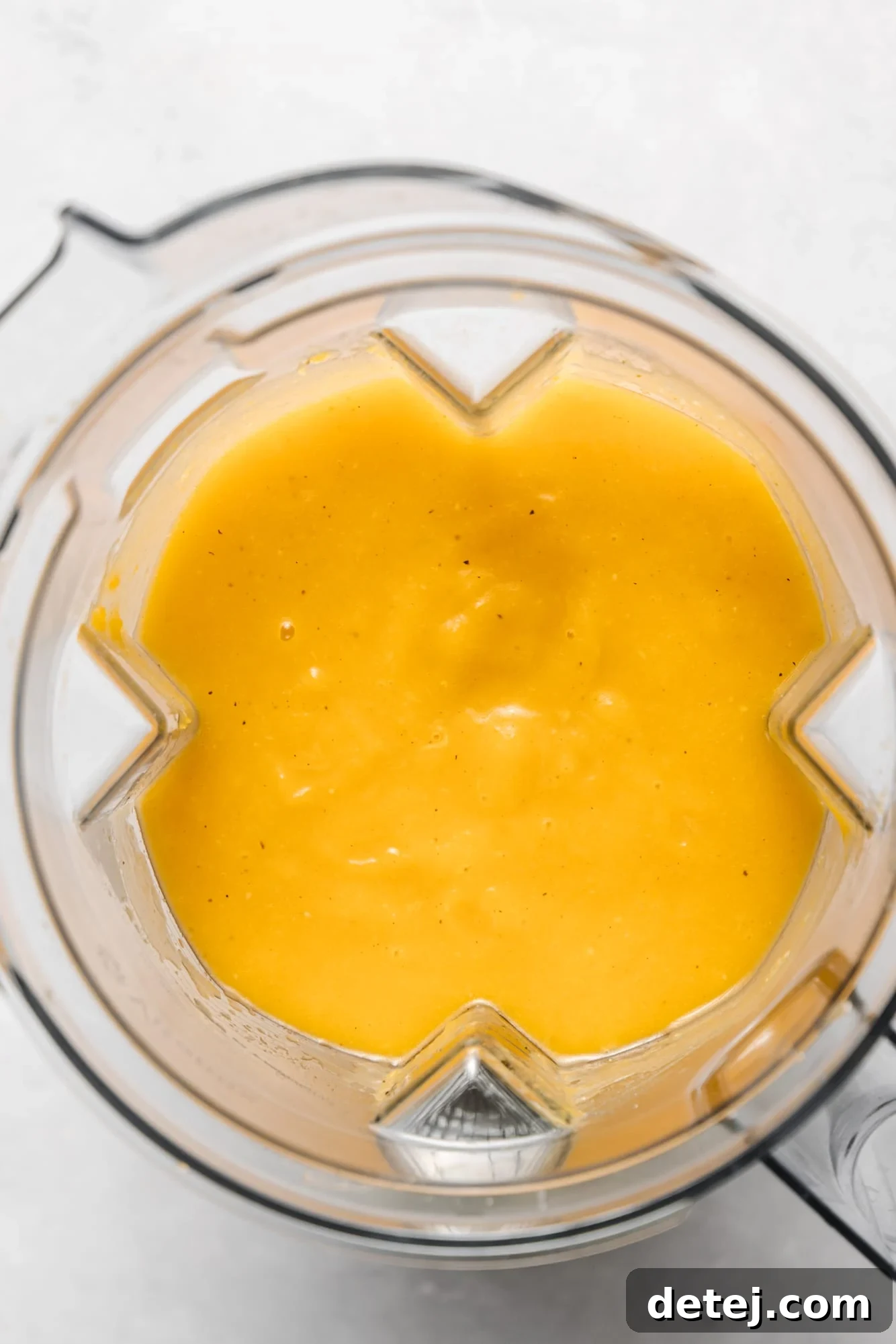 The smooth, golden-orange consistency of freshly blended butternut squash soup inside a large blender jar.