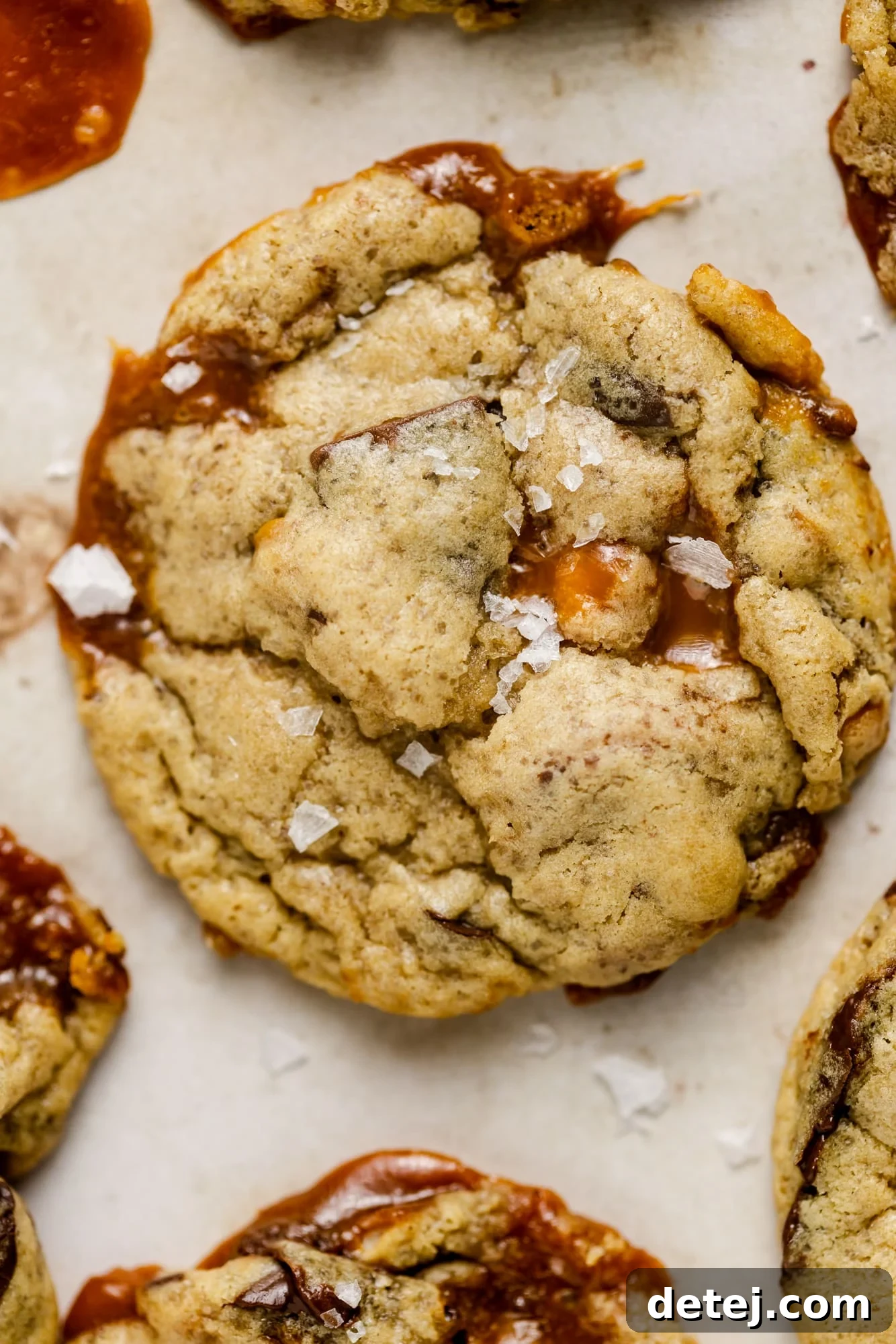 Close-up view of a single baked vegan kitchen sink cookie, highlighting its golden-brown exterior and visible chunks of rich chocolate and gooey caramel.