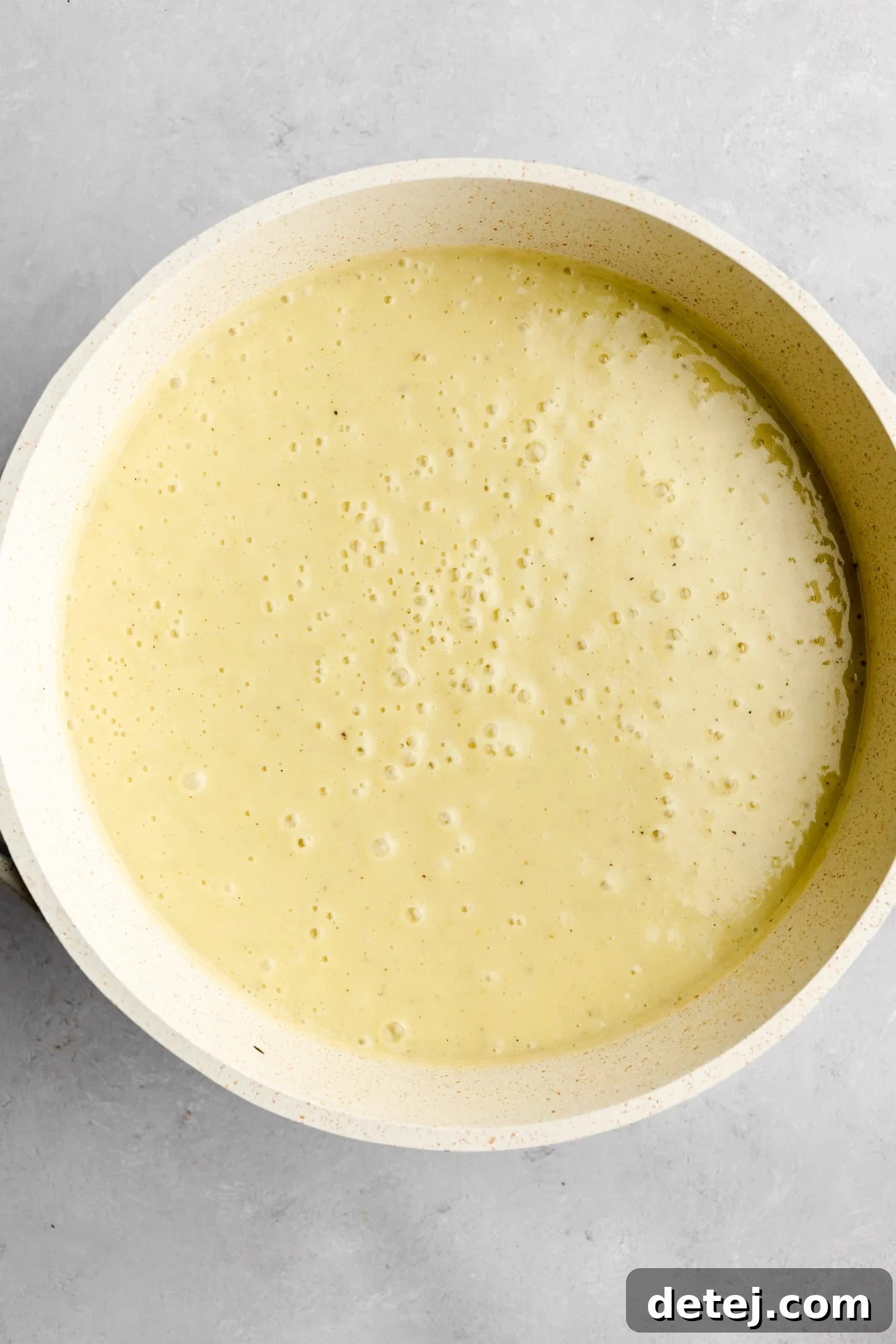 A large white pot filled with beautifully pureed, creamy Vegan Potato Leek Soup, showcasing its smooth, luscious texture after blending.