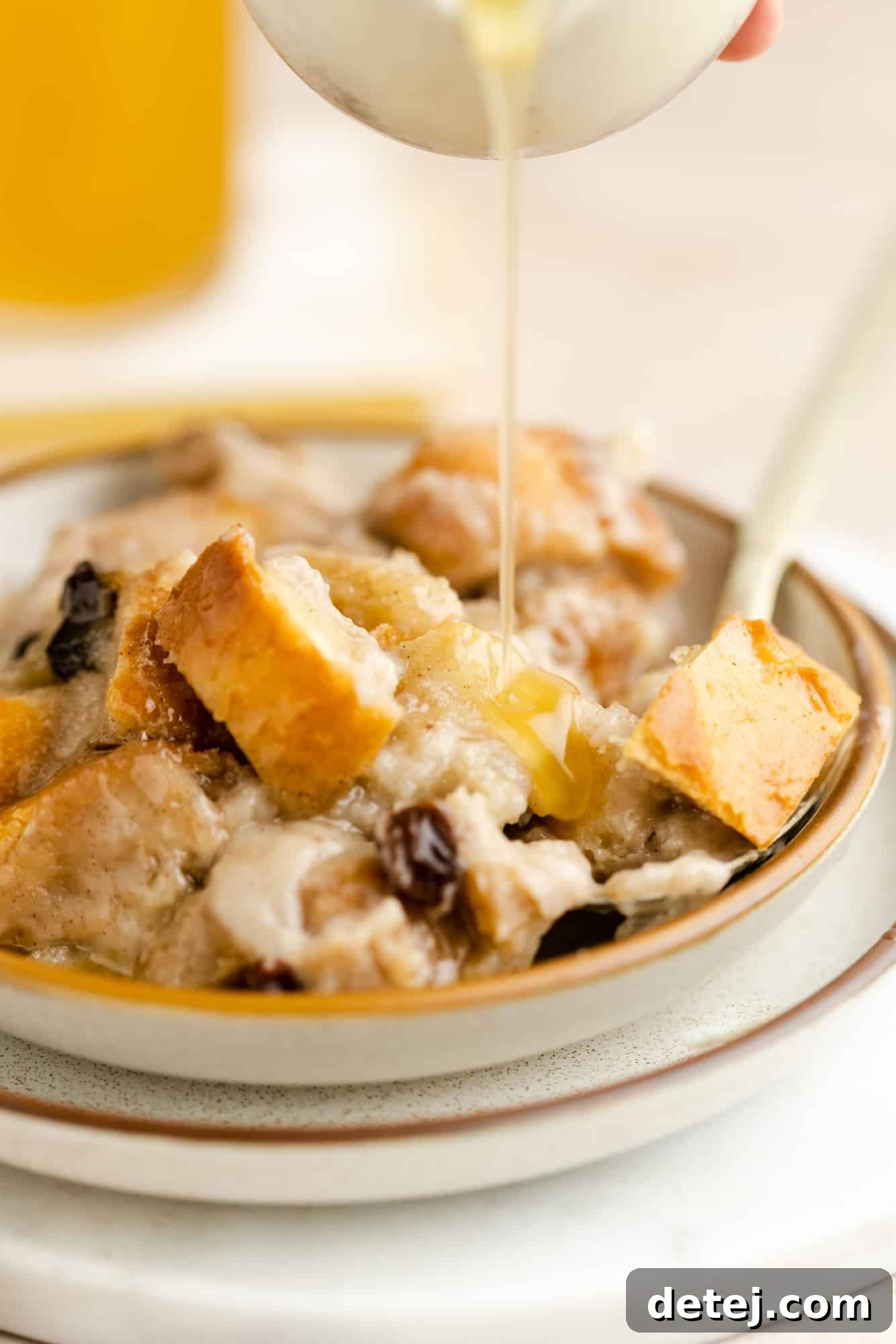 Decadent Vegan Bread Pudding 3 A rich bourbon glaze being drizzled over a warm scoop of vegan bread pudding in a white bowl, ready to be enjoyed.