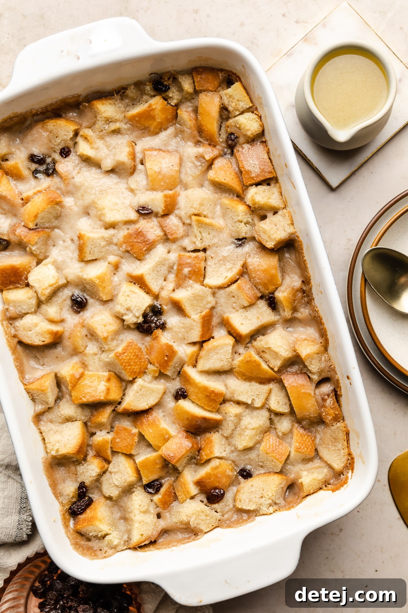 Decadent Vegan Bread Pudding 7 A freshly baked vegan bread pudding, golden brown on top, resting in a white rectangular baking dish.