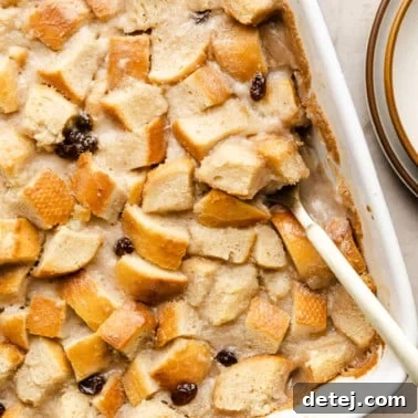 Decadent Vegan Bread Pudding 10 close up on a spoon taking a scoop of vegan bread pudding out of a white baking dish.