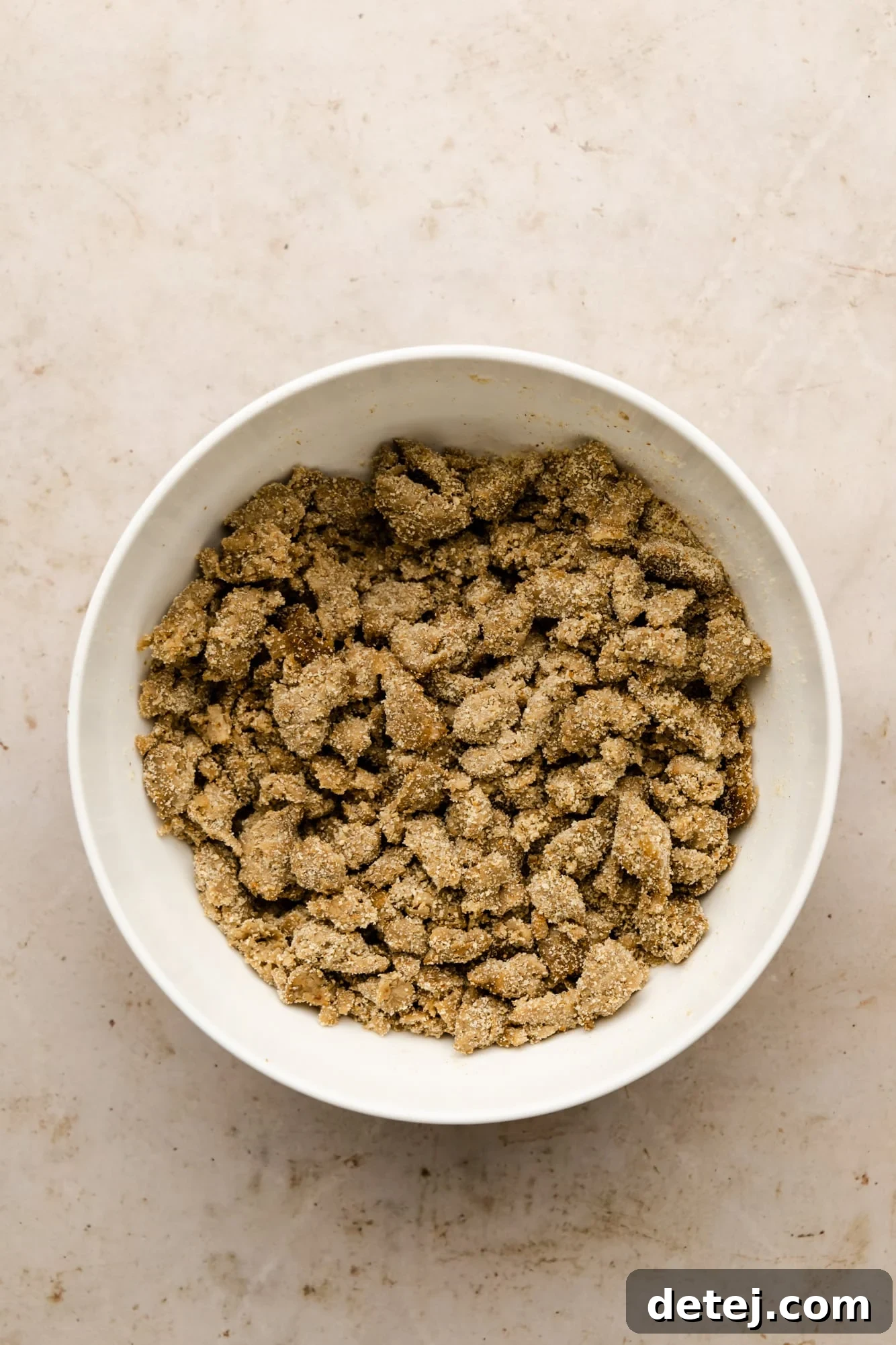 Vegan sausage crumbles mixed with breadcrumbs, presented in a white bowl, ready for assembly.
