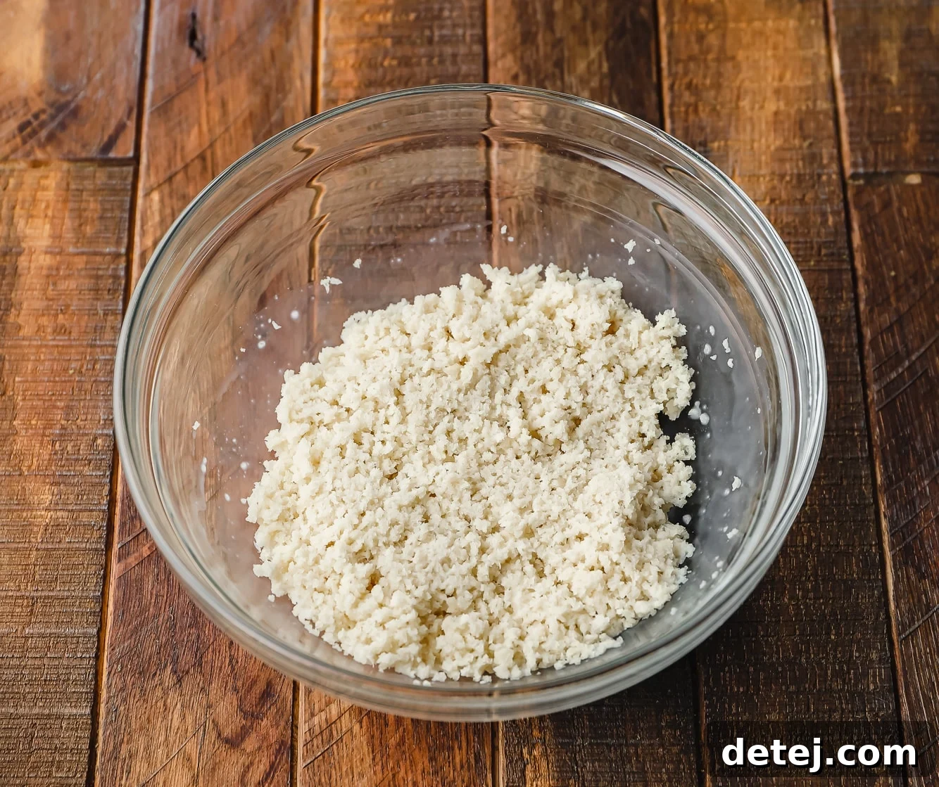 Next-Gen Meatballs 4 A close-up shot of moistened panko breadcrumbs resting in a clear glass bowl, ready for mixing.