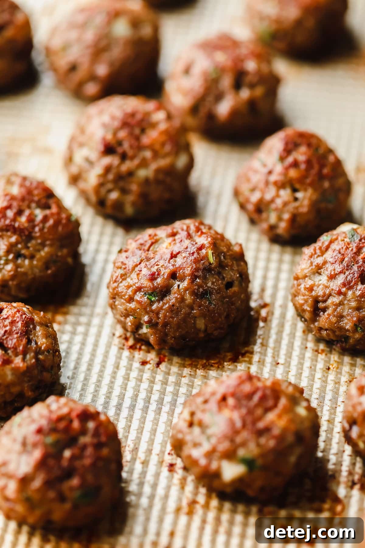 Rows of perfectly baked vegan meatballs arranged neatly on a sheet pan, golden brown and ready for sauce.