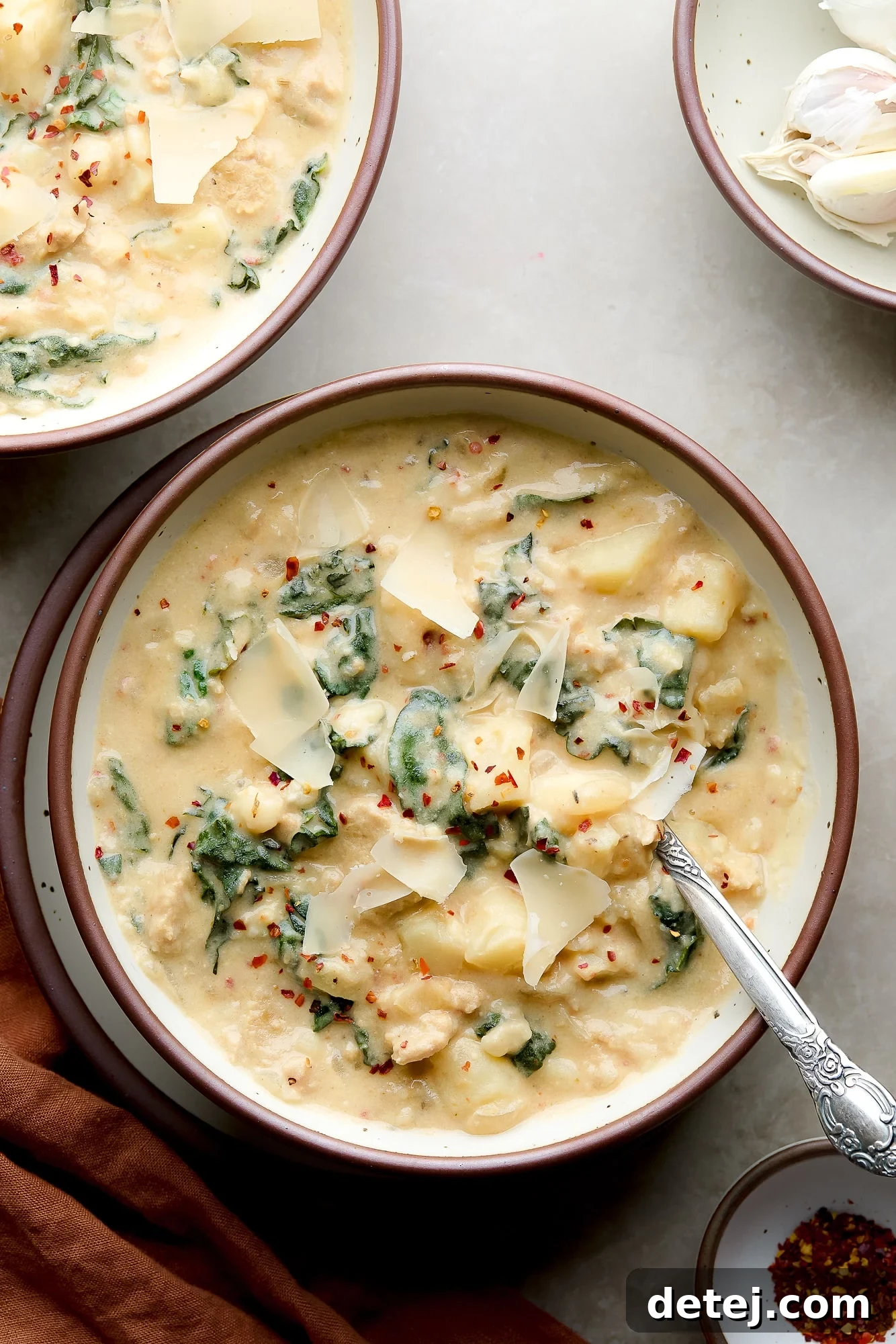 bowl of creamy vegan zuppa toscana with vegan parmesan on top