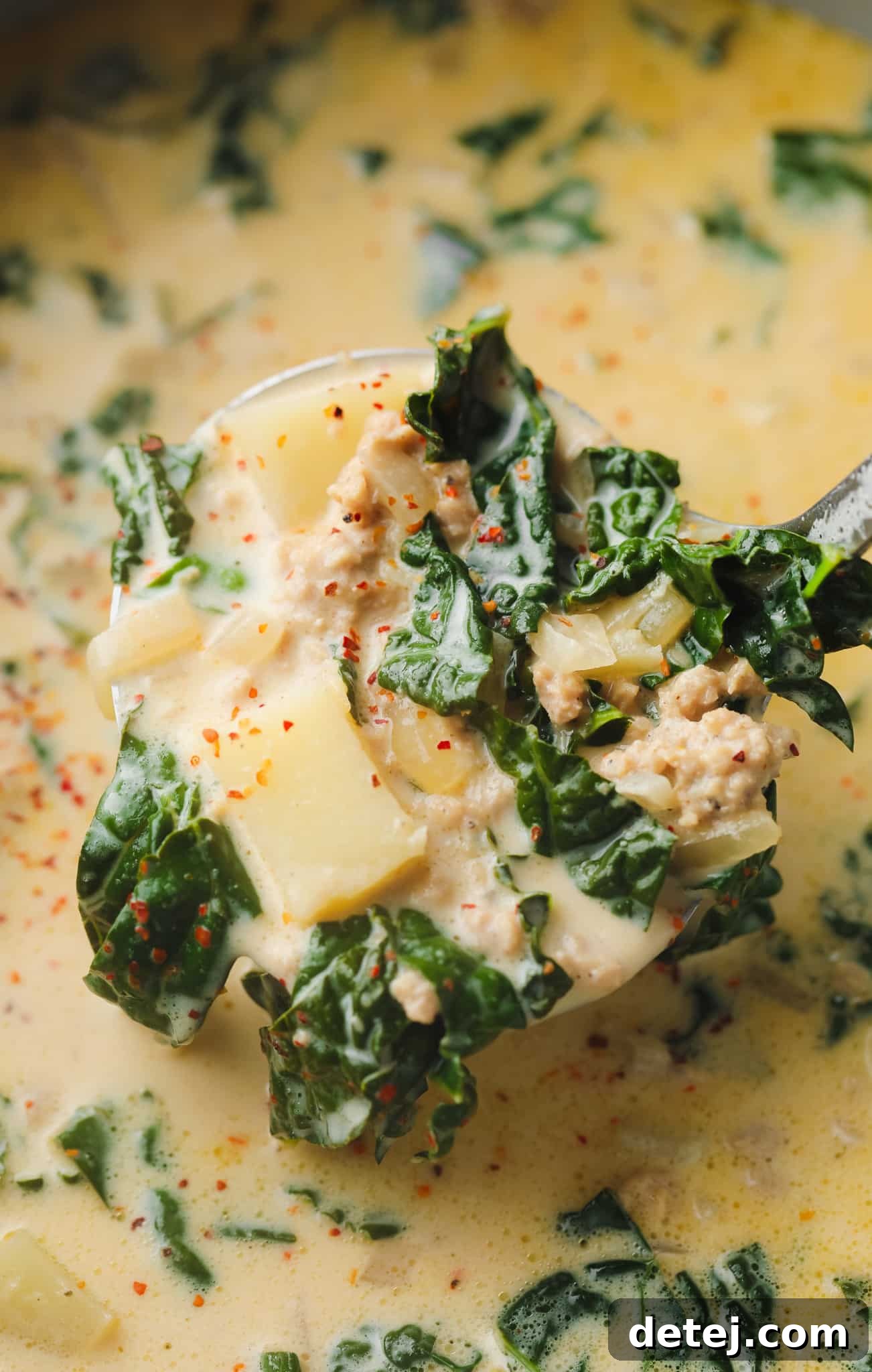 a soup ladle full of cooked vegan zuppa toscana soup.