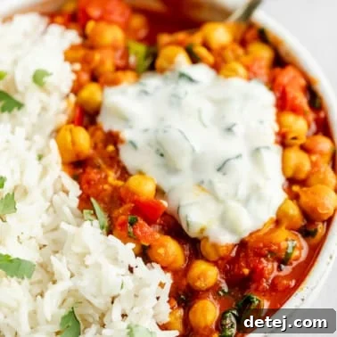 close up on a dollop of raita on top of chana masala in a bowl.