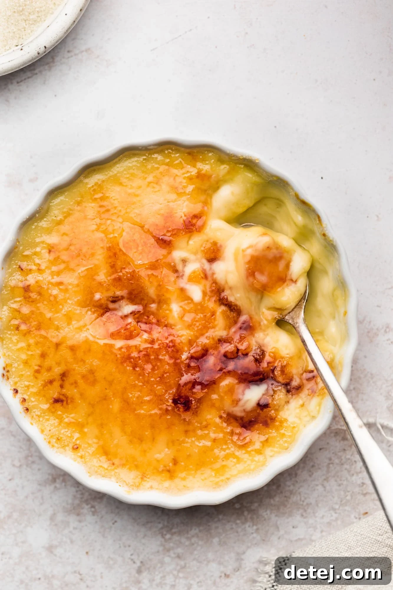 A metal spoon scooping a bite of golden-brown Vegan Creme Brulee.
