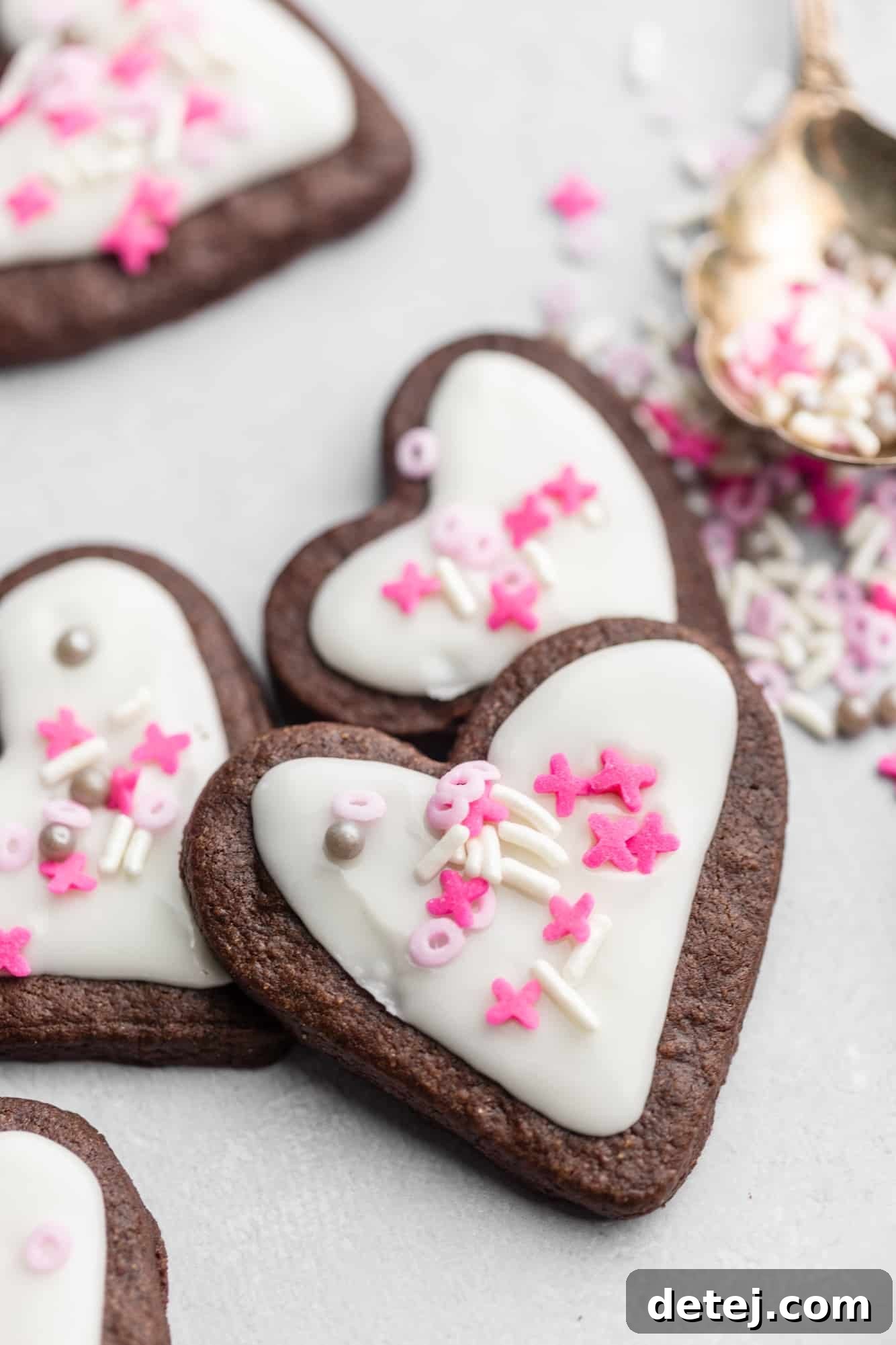 heart-shaped chocolate sugar cookies decorated with white icing and pink sprinkles.