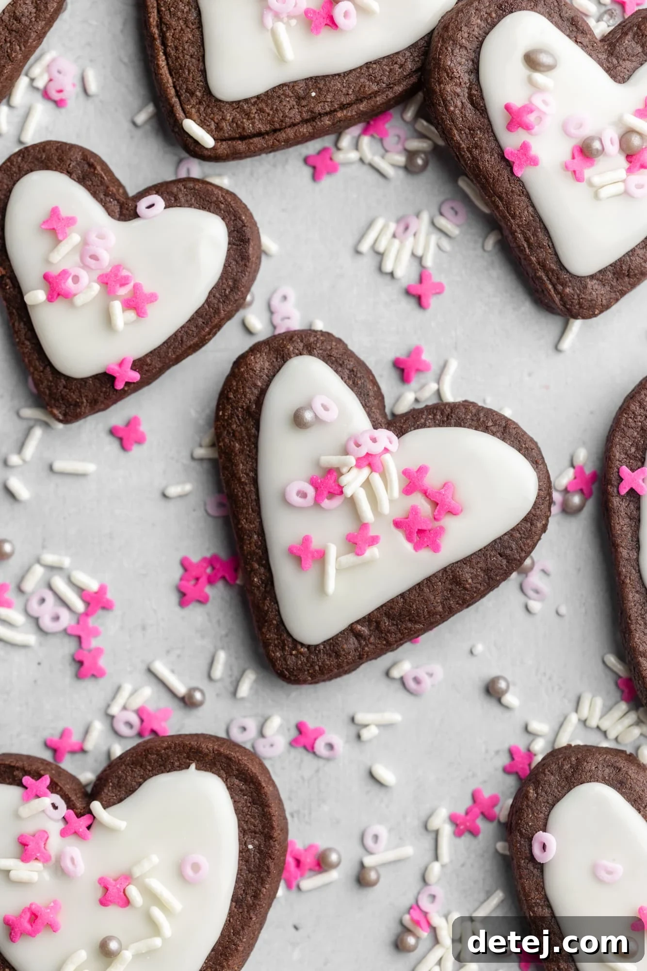heart-shaped chocolate sugar cookies decorated with white icing and pink sprinkles.