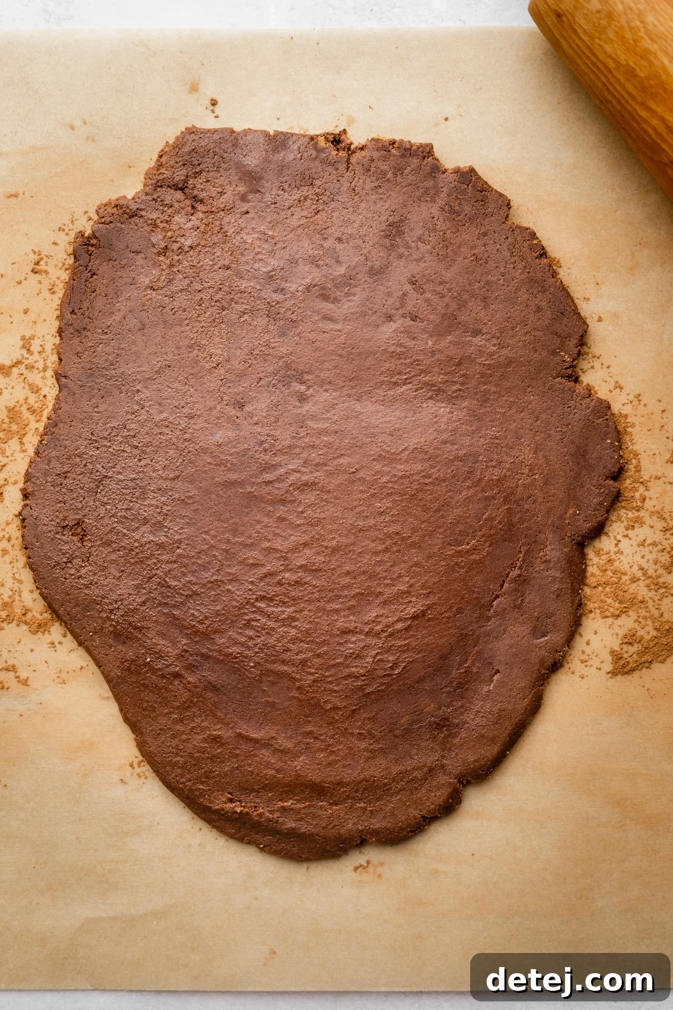 chocolate cookie dough rolled out into a flat layer on a parchment-lined surface.