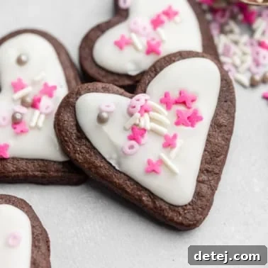heart-shaped chocolate sugar cookies decorated with white icing and pink sprinkles.