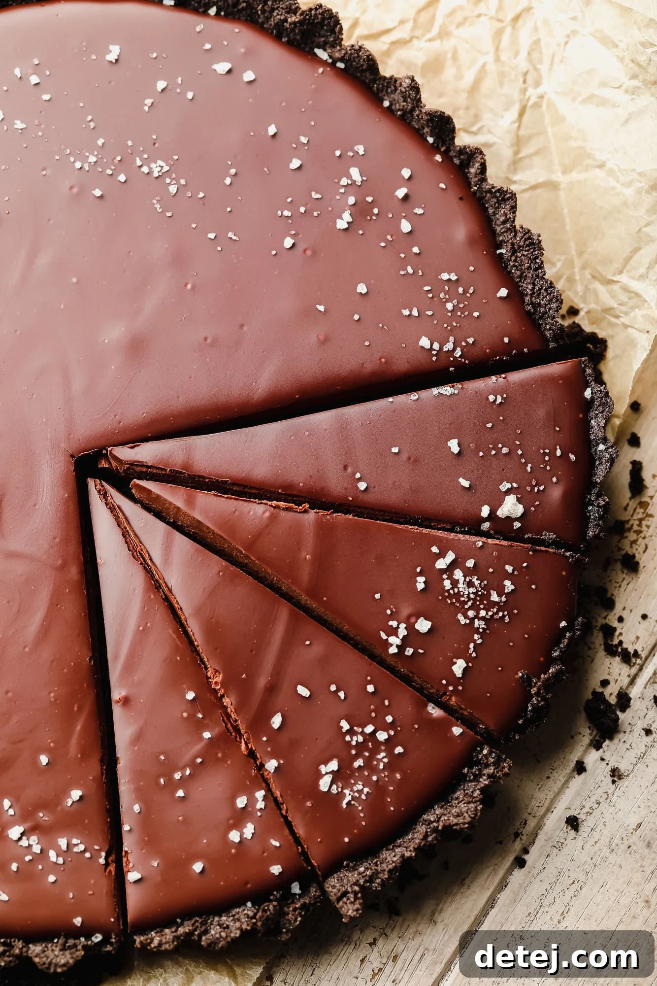 close up on a sliced vegan chocolate tart topped with flake salt.