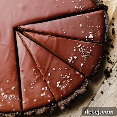 close up on a sliced vegan chocolate tart topped with flake salt.