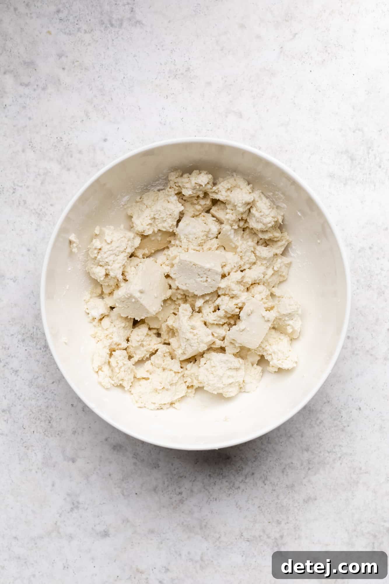 ripped tofu chunks in a white bowl.