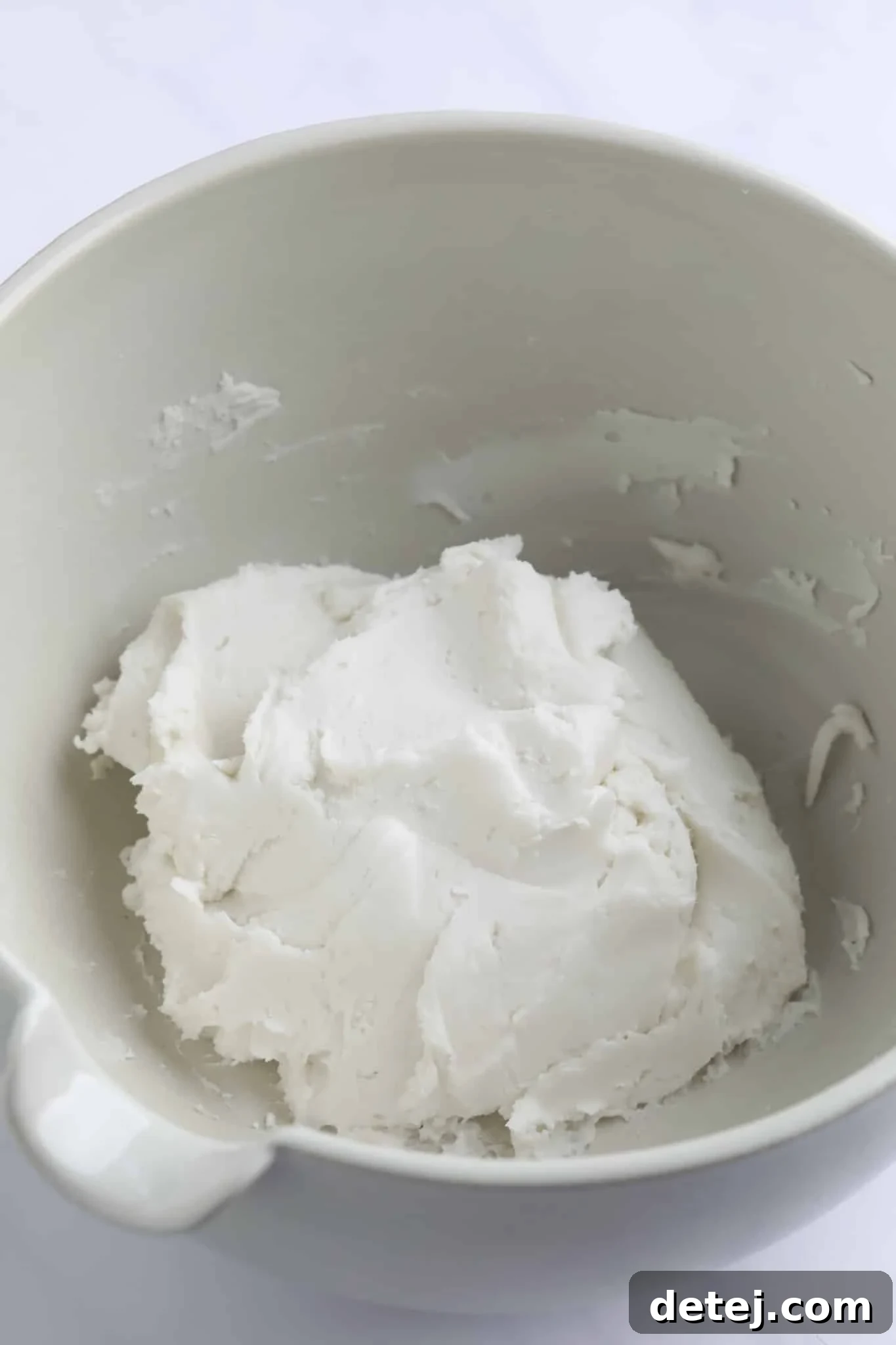 A perfectly smooth ball of white peppermint dough resting in a large white mixing bowl, ready for shaping.