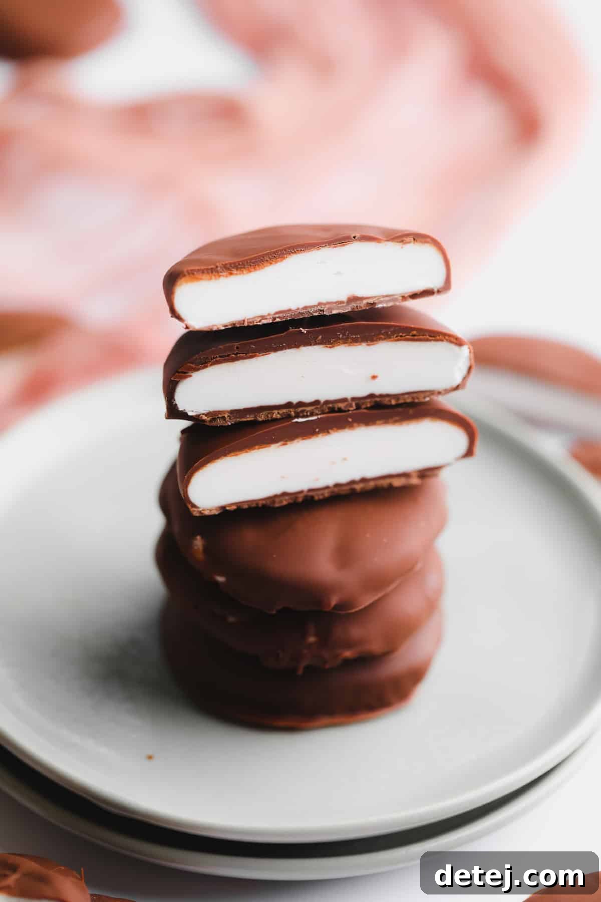 A close-up shot of several vegan peppermint patties, some sliced open, neatly stacked on a small ceramic plate, showcasing their inviting texture.