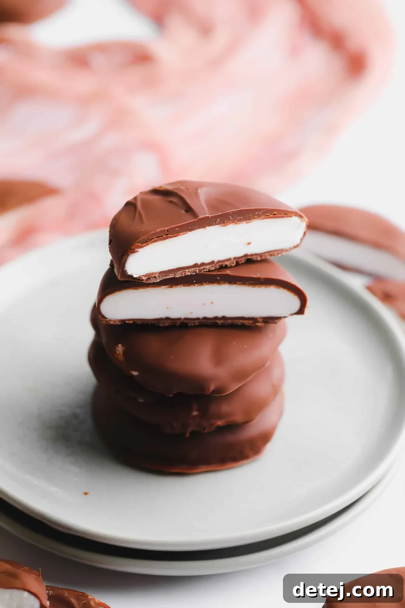 Another enticing view of a stack of vegan peppermint patties, expertly cut in half to showcase the vibrant white peppermint filling, presented on a small plate.