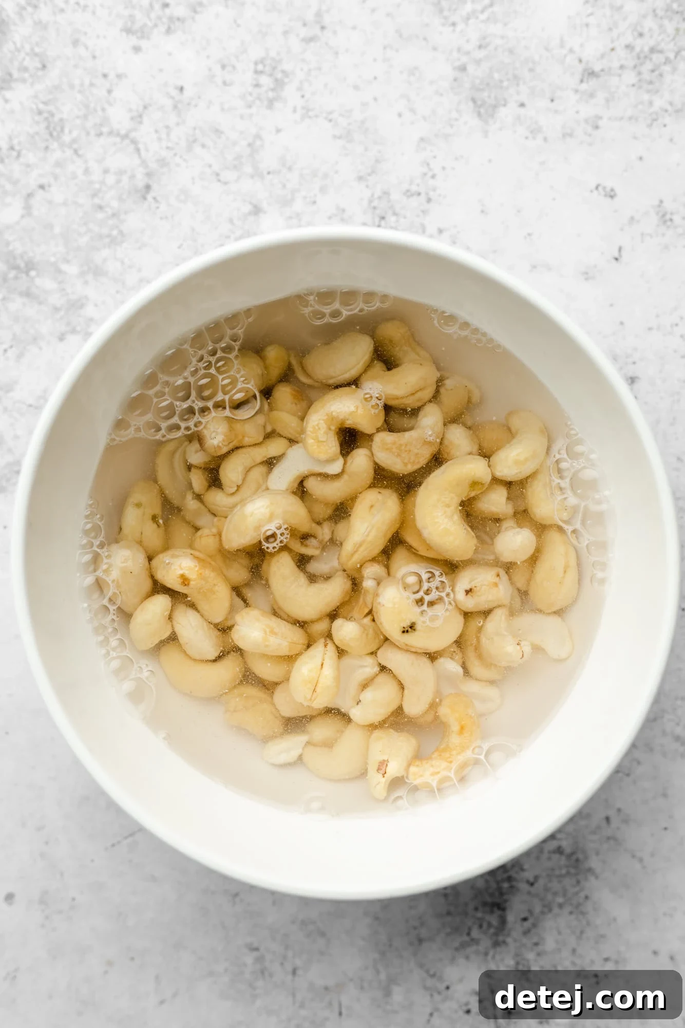 Smoky Chipotle Magic 4 Raw cashews soaking in a bowl of hot water, preparing for blending.