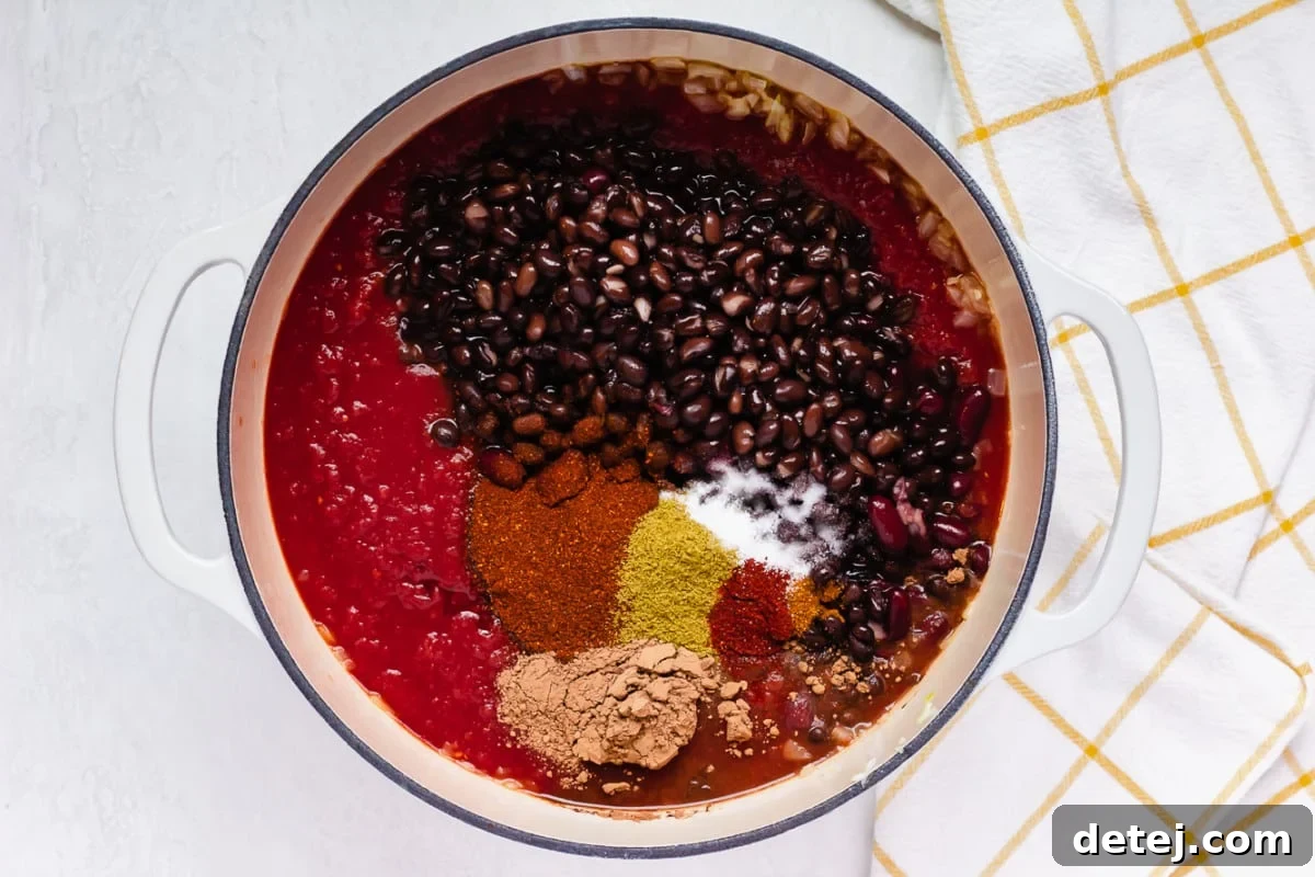 black beans, tomato sauce and spices in a white pot, not yet stirred together.