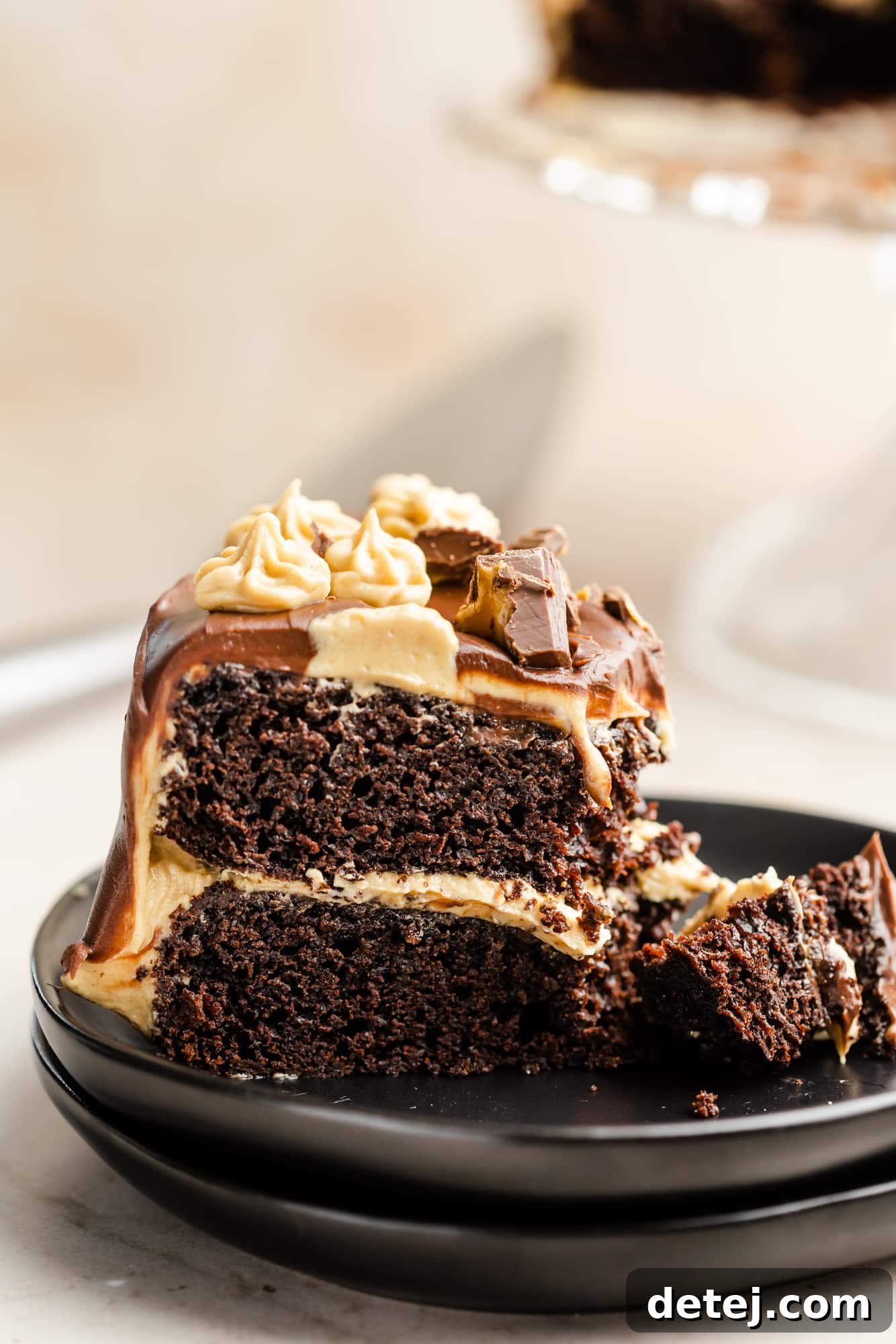 Decadent Chocolate Peanut Butter Dream 2 close up on a slice of chocolate peanut butter cake on a black plate.