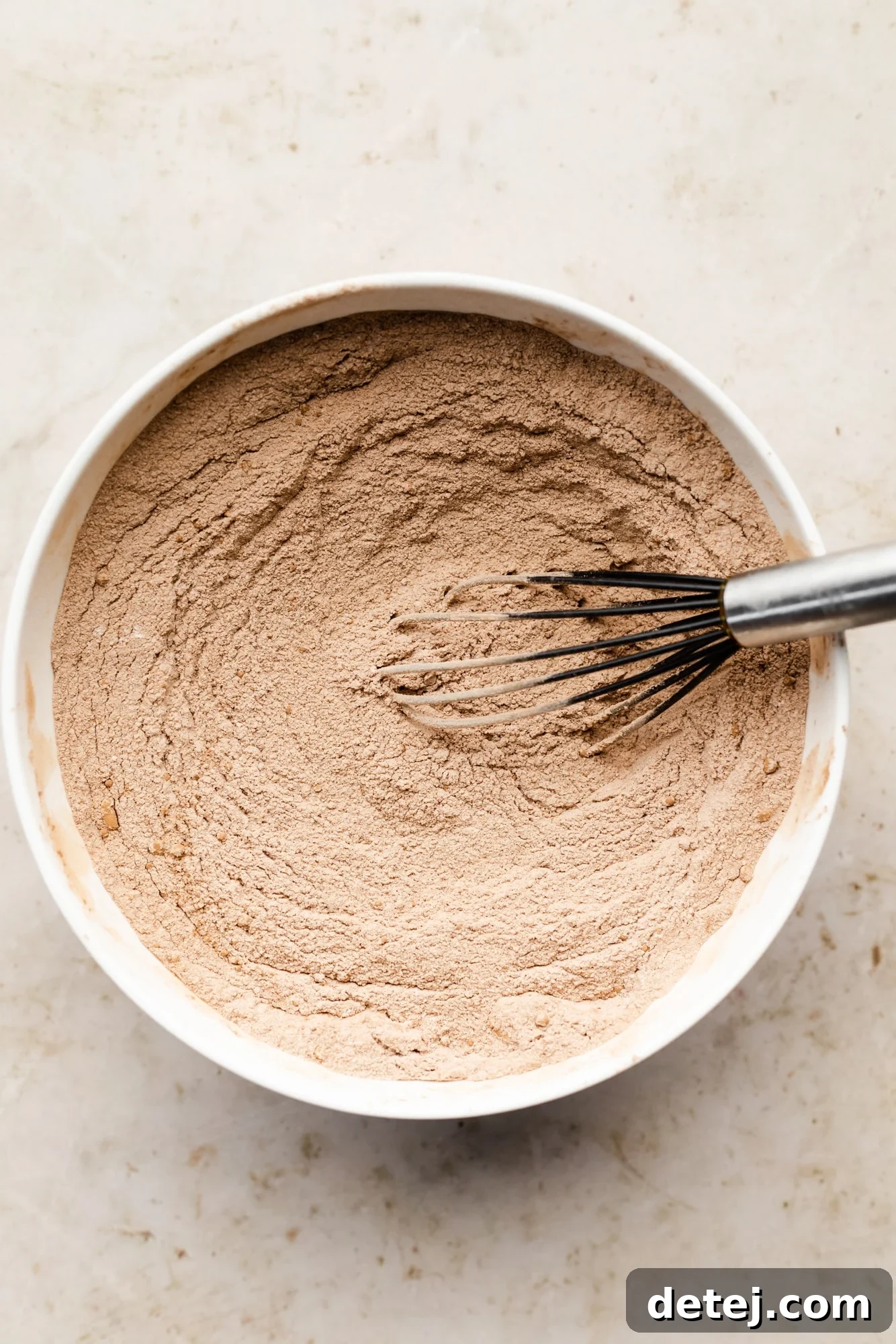 Decadent Chocolate Peanut Butter Dream 5 dry chocolate cake mix and a whisk in a large white bowl.
