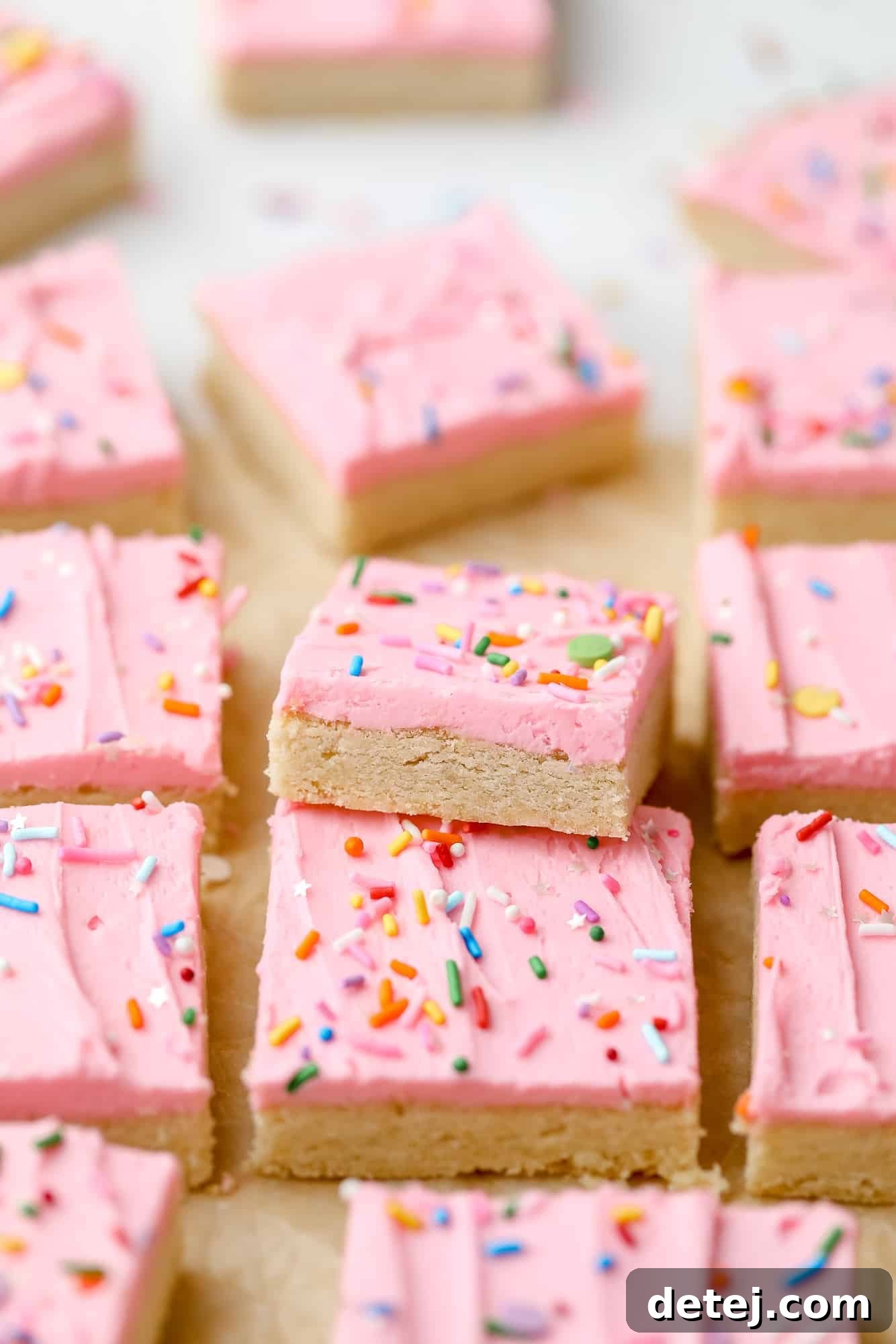 More rows of vegan sugar cookie bars, showcasing the uniform pink frosting and colorful sprinkles, ready for serving.