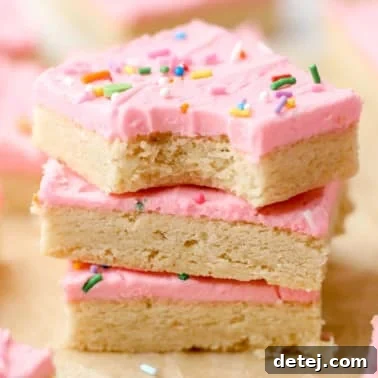 a stack of 3 sugar cookie bars decorated with pink frosting on top of each other.