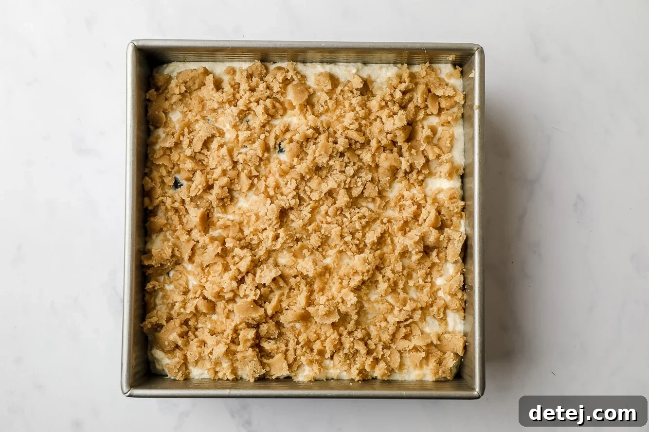 unbaked coffee cake topped with streusel in a square cake pan.