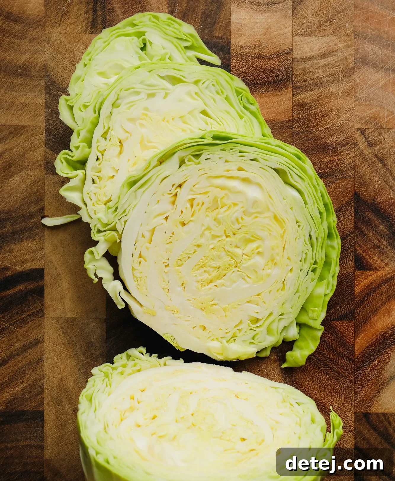 Raw green cabbage cut into thick, circular slices, ready for seasoning and roasting, displaying its vibrant color and sturdy structure.