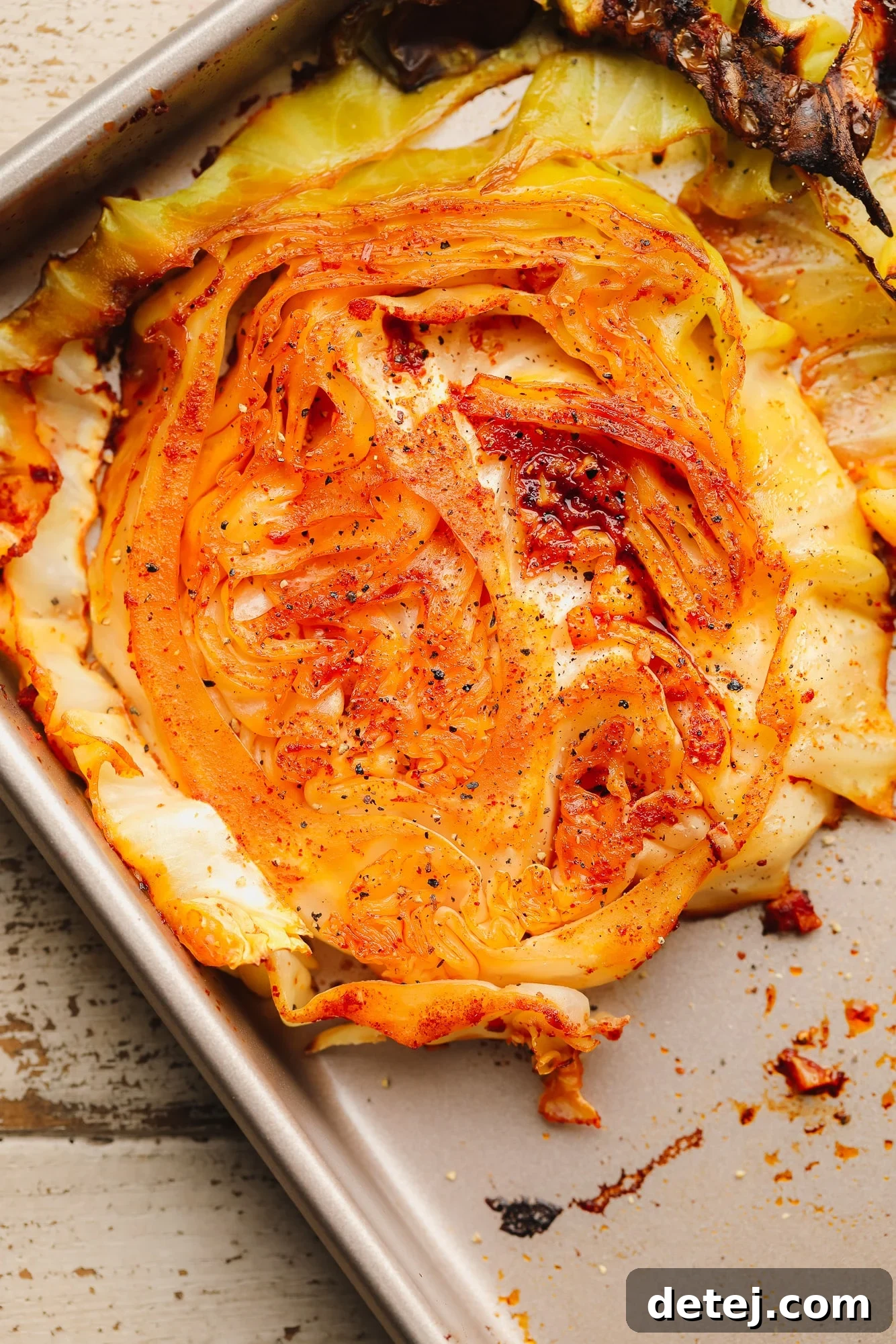 A close-up view of a perfectly roasted cabbage steak on a metal baking sheet, showing its golden-brown edges and soft interior.