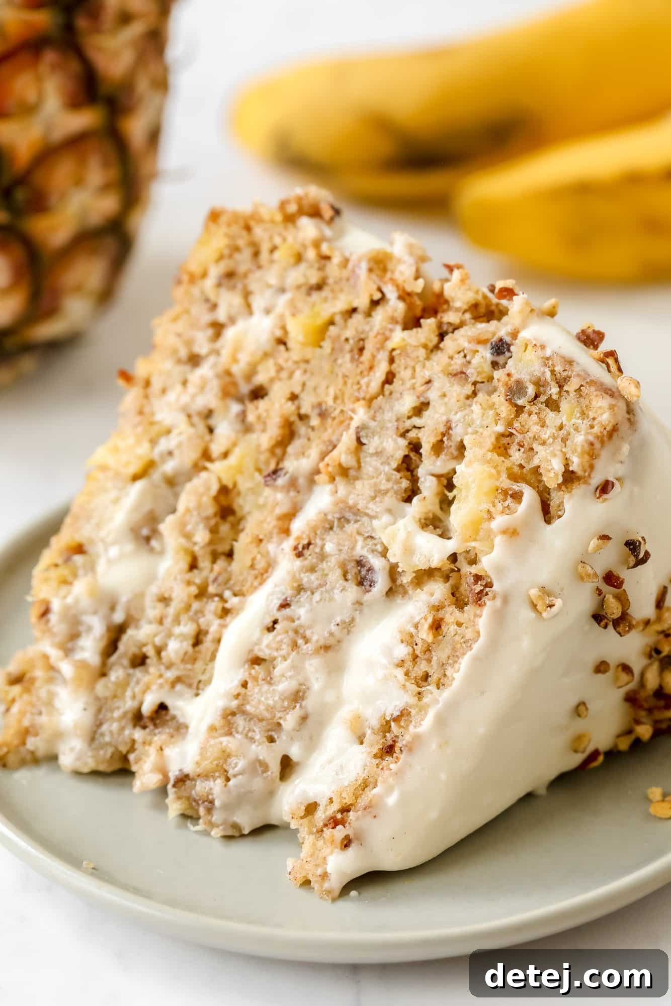 a slice of vegan hummingbird cake on a grey plate, showcasing its moist texture and creamy frosting.