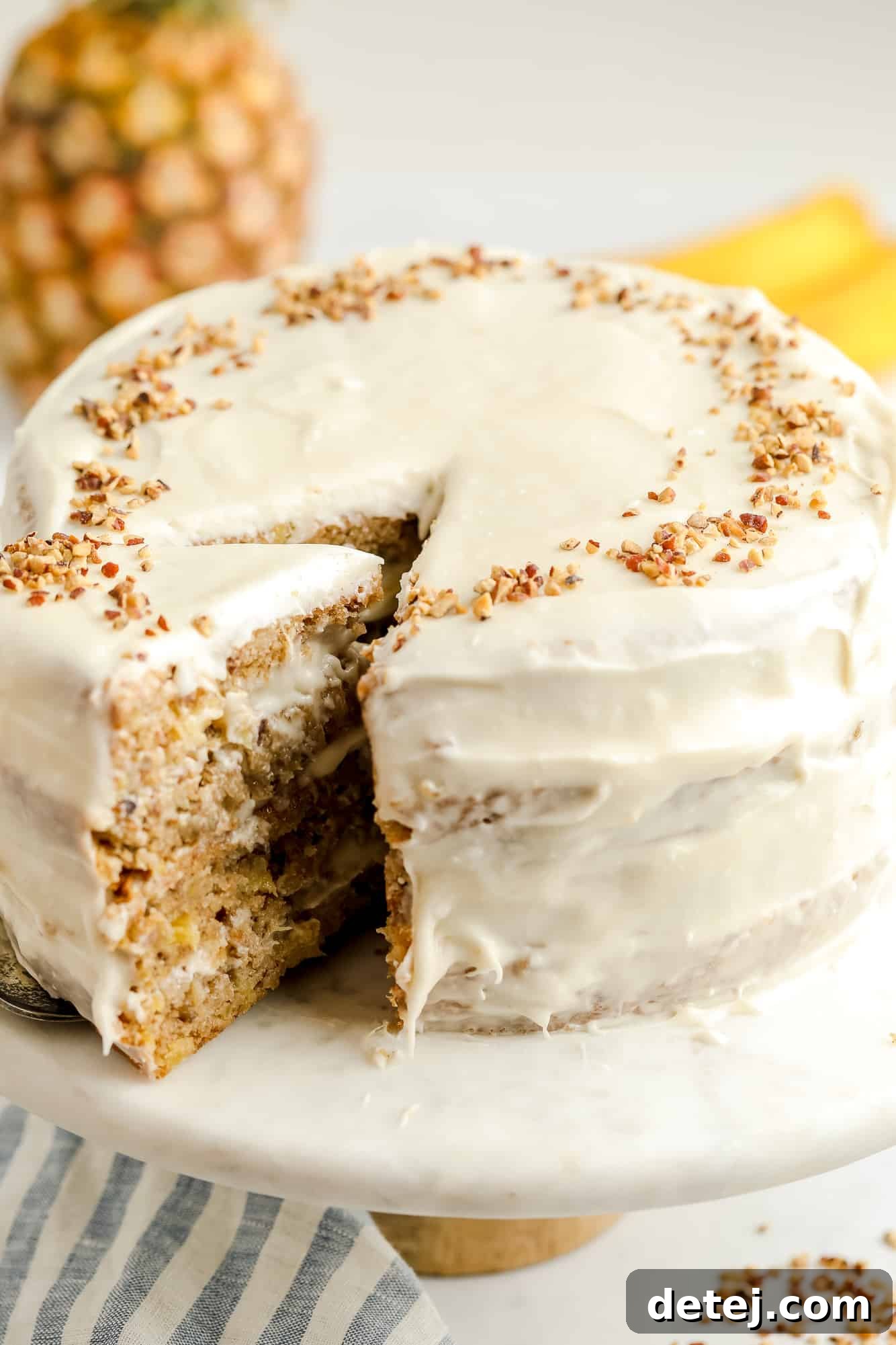 a cream cheese frosted-vegan hummingbird cake with a slice being removed, showing its rich layers.