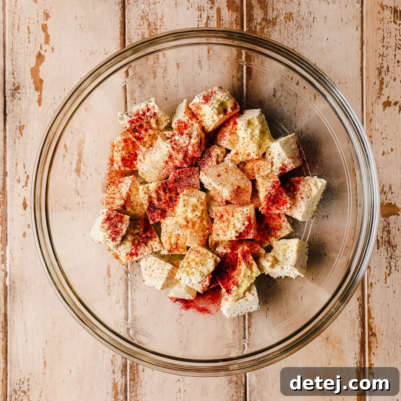 tofu pieces covered in seasonings in a glass bowl.