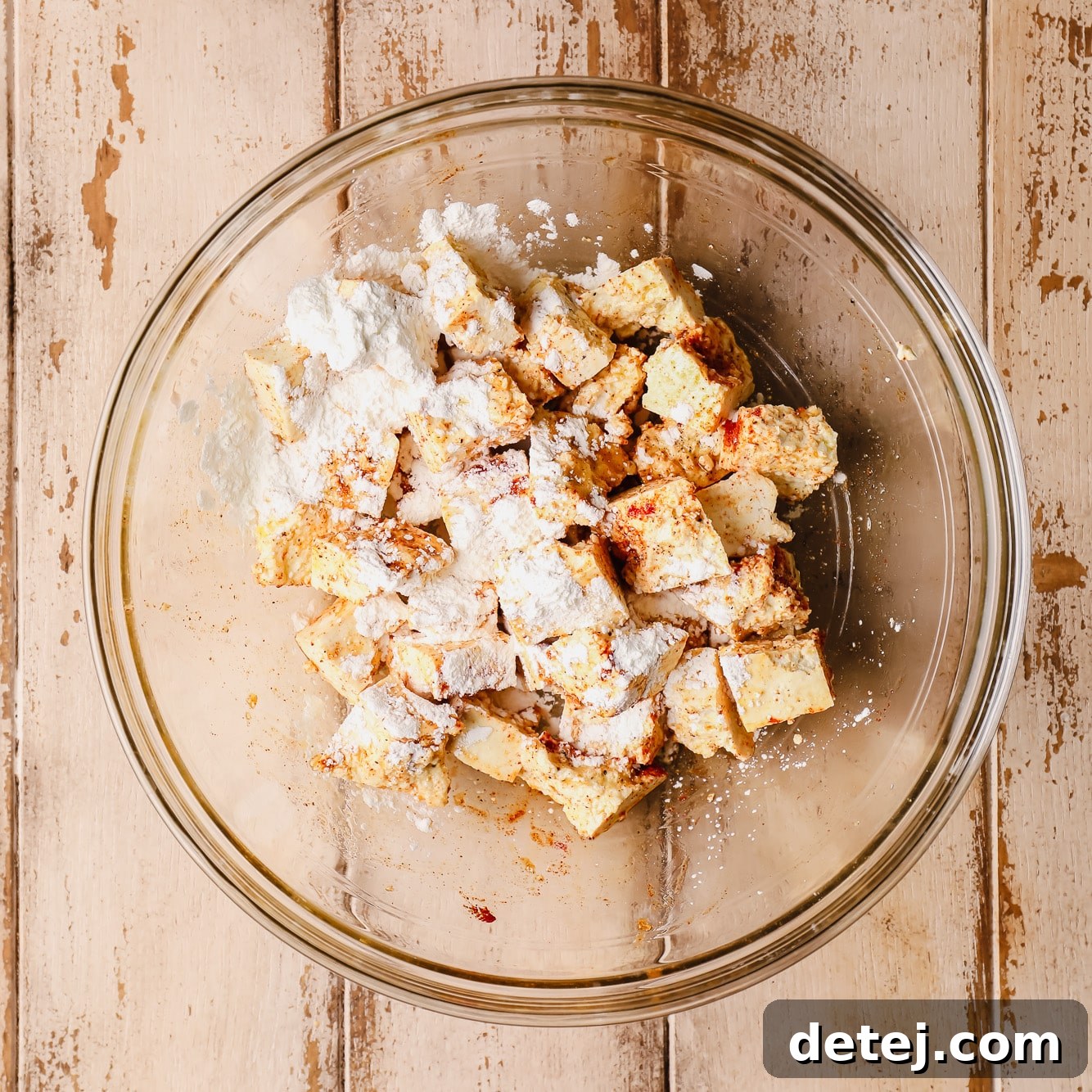 tofu pieces covered in cornstarch in a glass bowl.