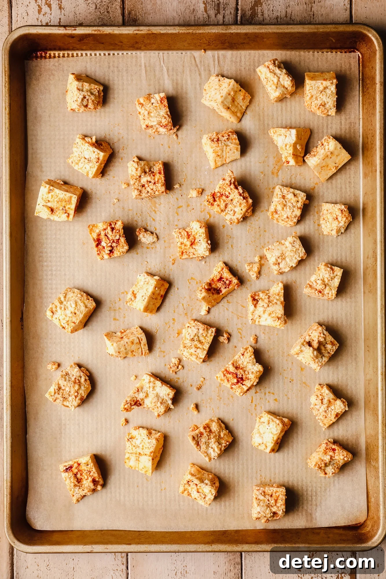 seasoned raw tofu pieces in rows on a baking sheet.